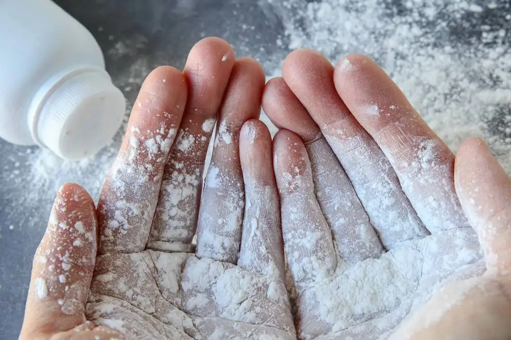 Hands holding and sprinkling white talcum powder.